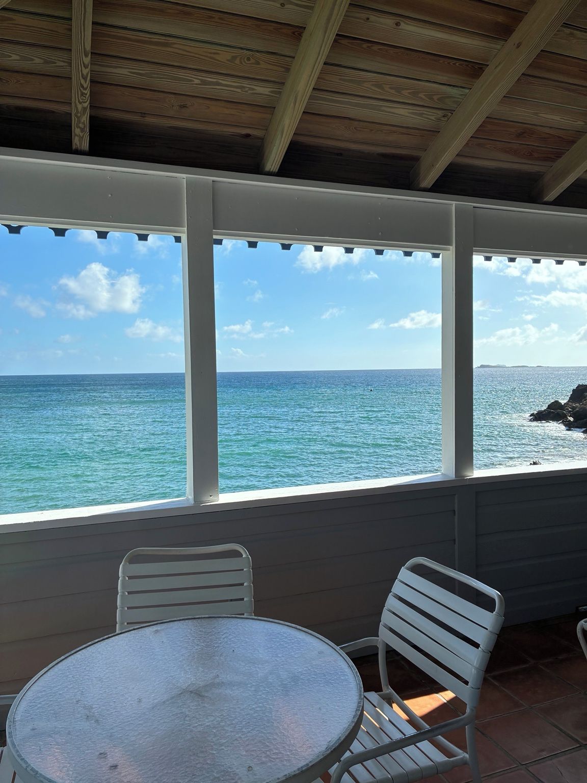 A covered outdoor seating area with a view of the ocean.