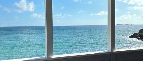 A covered outdoor seating area with a view of the ocean.