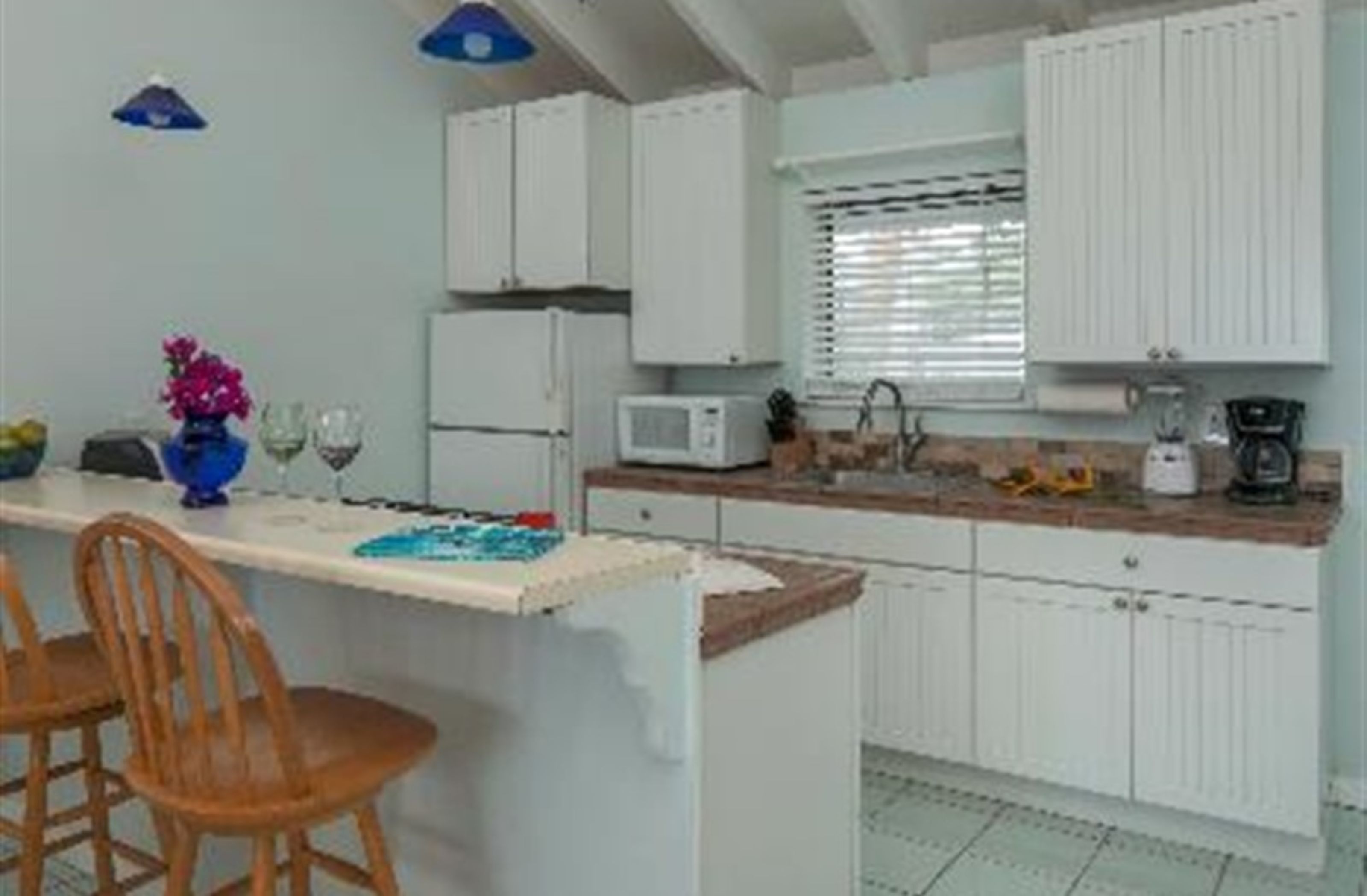 A kitchen with white cabinets, a microwave, and a coffee maker on the counter.