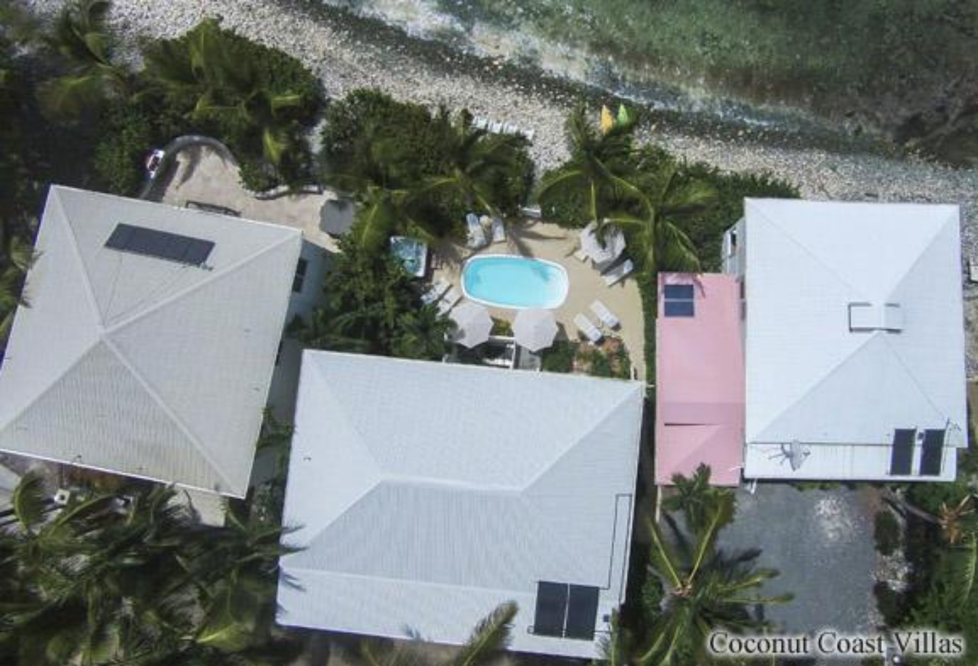 Un resort con tre ville, una piscina e palme.