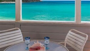 A table with two chairs and a glass of water, overlooking a turquoise ocean. - Coconut Coast Villas (St. John)