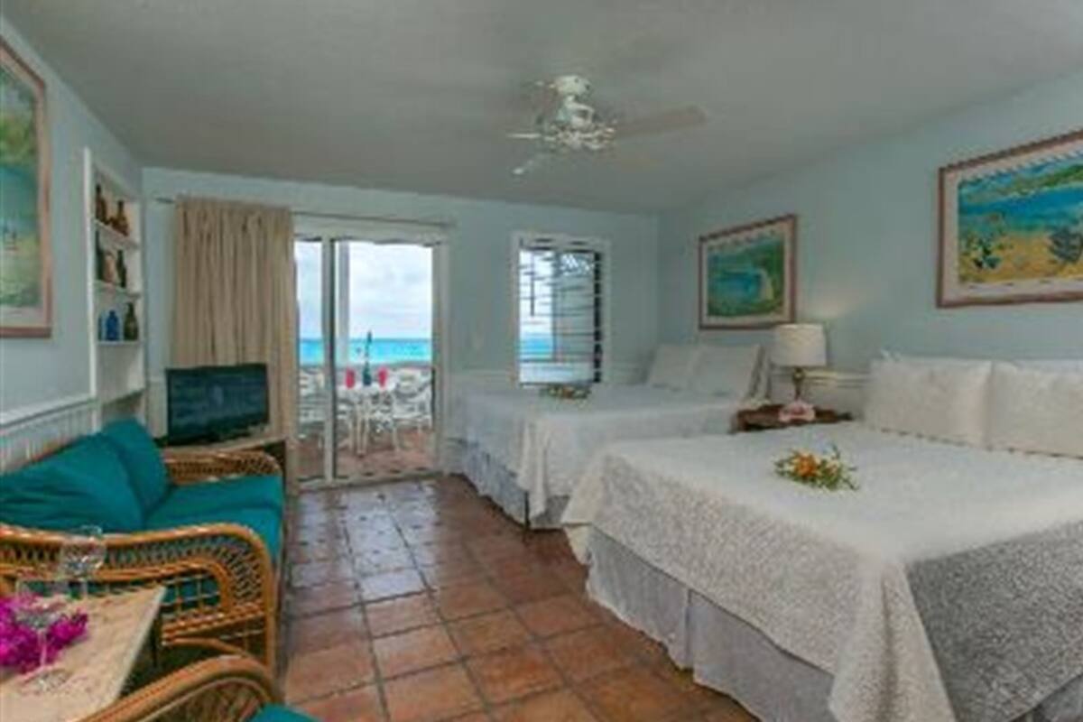 A hotel room with a bed, a chair, a table, and a view of the ocean.