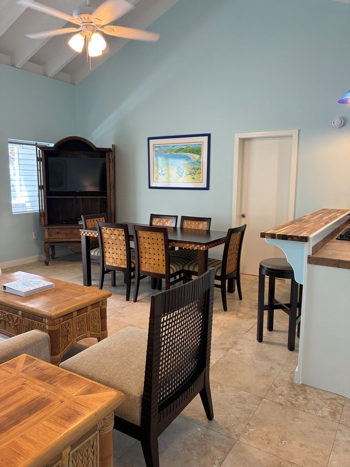 A dining area with a table, chairs, a television, and a framed picture on the wall.