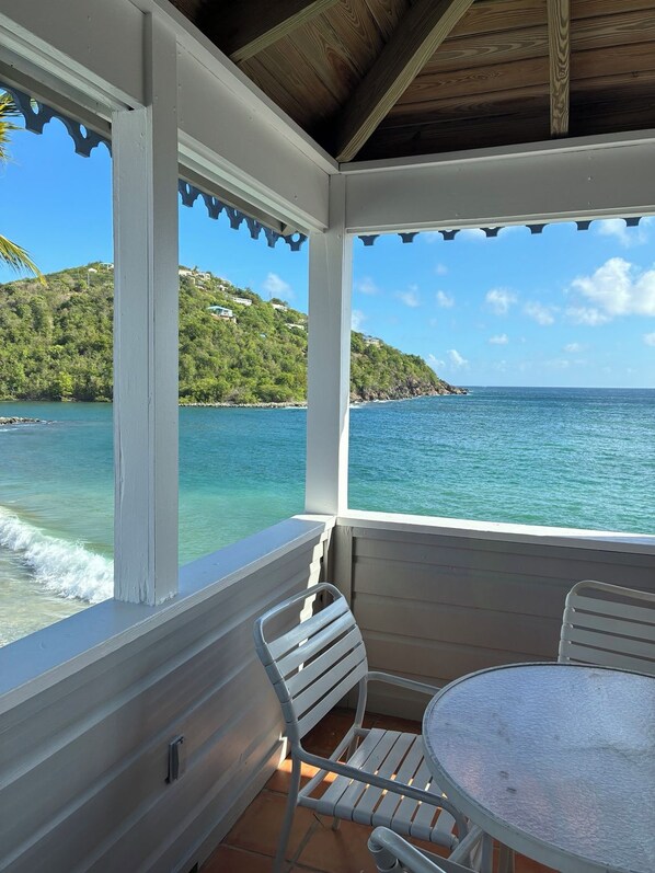 A covered outdoor seating area with a view of the sea and a hillside. - Coconut Coast Villas (St. John)