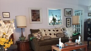 Un salon chaleureux avec un canapé, une table basse sur laquelle sont posés des livres, une lampe et des objets de décoration.