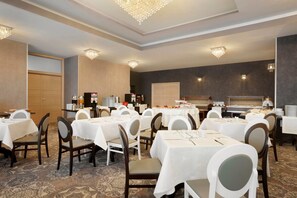 A hotel dining area with multiple tables and chairs, a buffet setup, and a large conference room. - Ramada by Wyndham Constanta (Constanta)