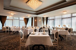 A banquet hall with round tables, white tablecloths, and candle centerpieces. - Ramada by Wyndham Constanta (Constanta)
