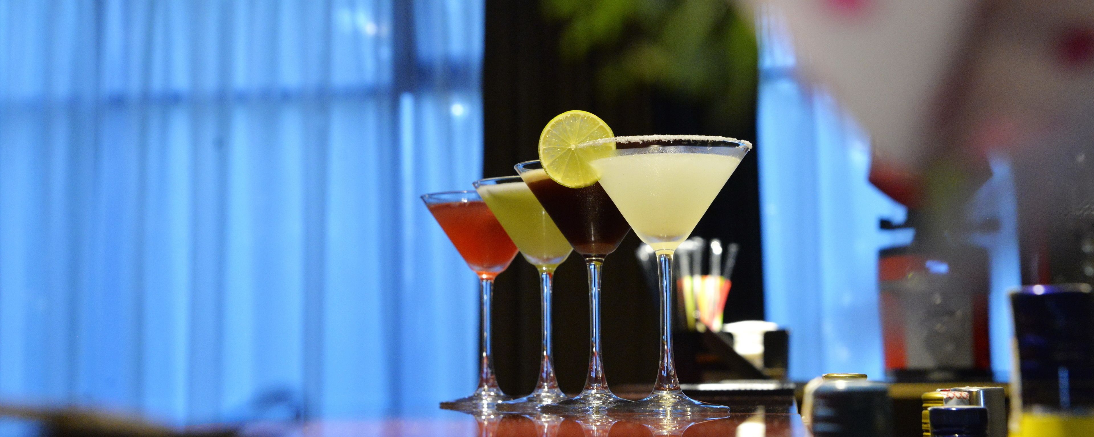 Un bar proposant divers cocktails servis dans des verres à martini, décorés d’une tranche de citron vert et dont le bord est givré au sel.