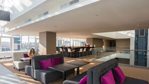 A spacious lobby with modern furniture, large windows, and a city view. - Ramada by Wyndham Constanta (Constanta)