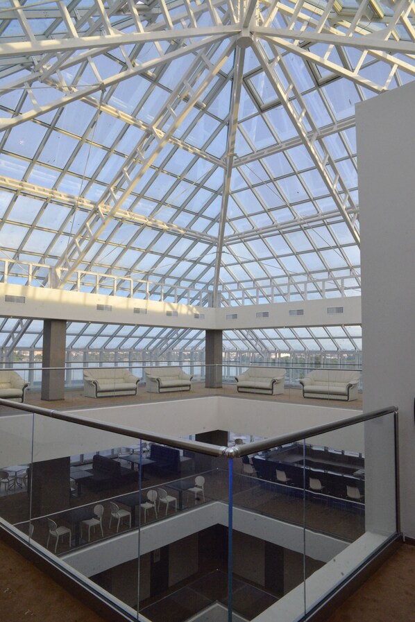 A spacious atrium with a glass ceiling, multiple seating areas, and a view of the outside. - Ramada by Wyndham Constanta (Constanta)