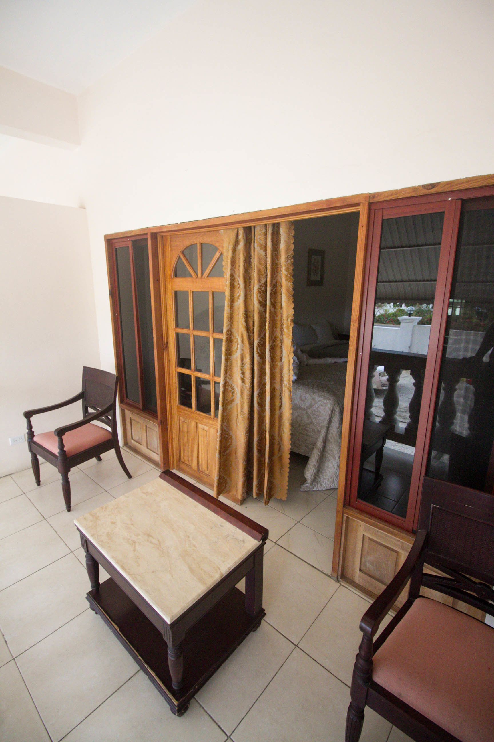 Una habitación con una cama, una puerta de madera, una silla y una mesa.