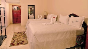 A hotel room with two beds, a wooden wardrobe, a mirror, and a red door. - Chateau Margarite Hotel (Montego Bay)
