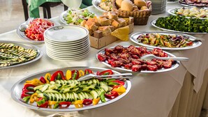 Una mesa de buffet con diversos platos, entre ellos ensaladas, verduras a la parrilla y pan.