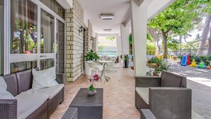 Un área de estar al aire libre con techo, amueblada con muebles de mimbre, una mesa y sillas.