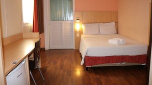 A hotel room with a bed, a desk, a chair, a wardrobe, and a window with curtains. - Samba Itaboraí (Itaborai)