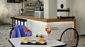 Un restaurante con zona de bar, vistas de la ciudad y una mesa con una bebida y aperitivos.