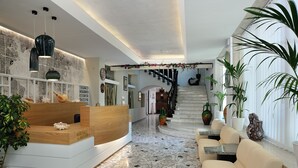 Zona de recepción con un escritorio de madera, piso de mosaico y una escalera que sube a los pisos superiores.