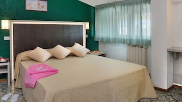 Un letto rifatto con un poggiatesta, un comodino con una lampada, una sedia e un termosifone.