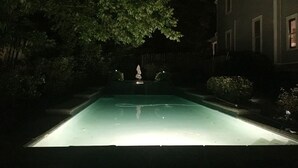 Ein Schwimmbecken bei Nacht mit einer Statue in der Mitte.