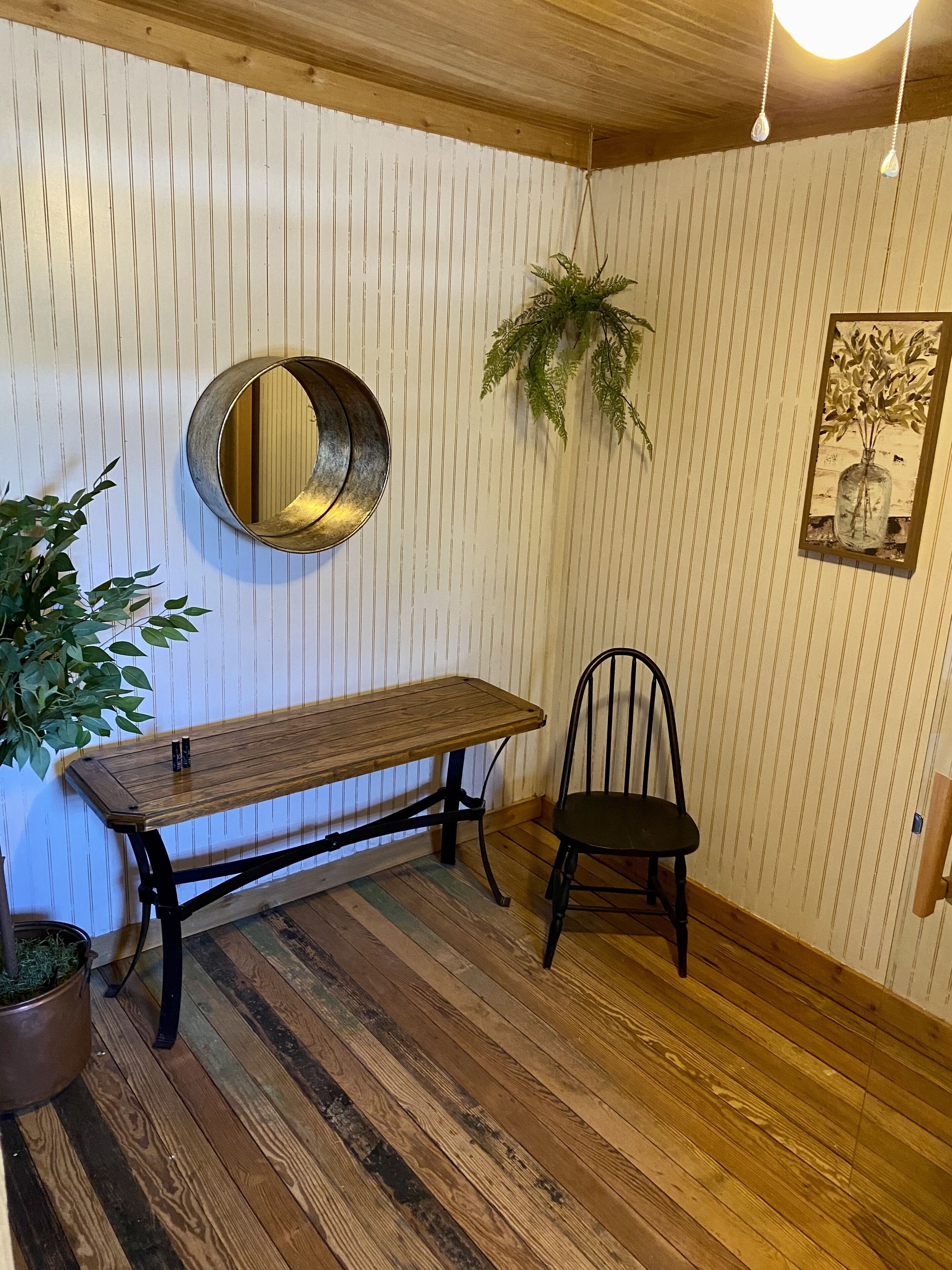 Een kamer met een houten tafel, een stoel, een hangspiegel en een potplant.