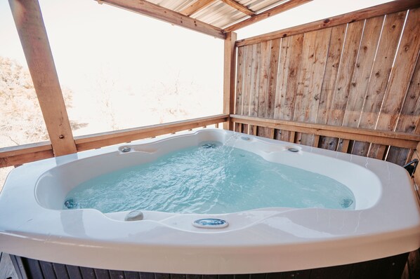 A hot tub in an outdoor wooden deck area. - City on a Hill at Spring Creek (Fredericksburg)