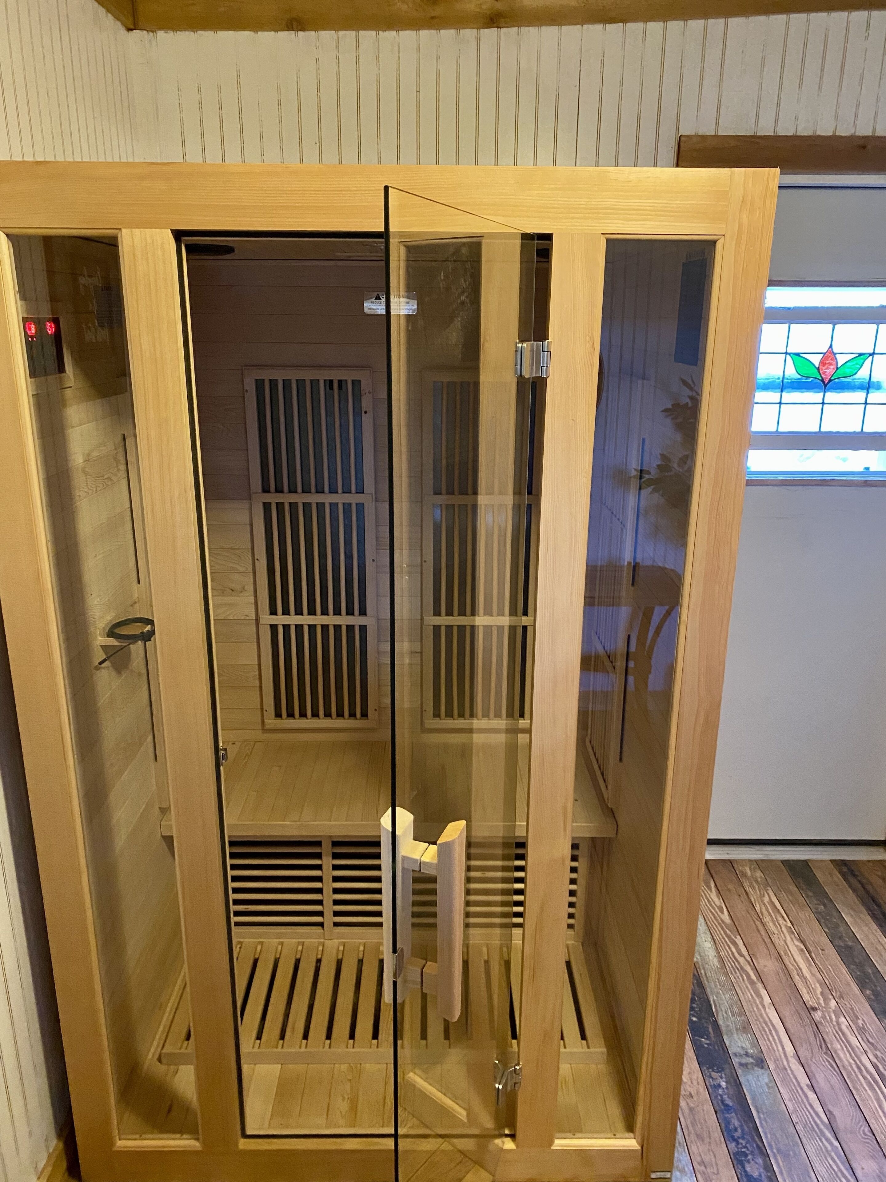 Eine Sauna mit Holzvertäfelung, einer Glastür und einem Lüftungssystem.