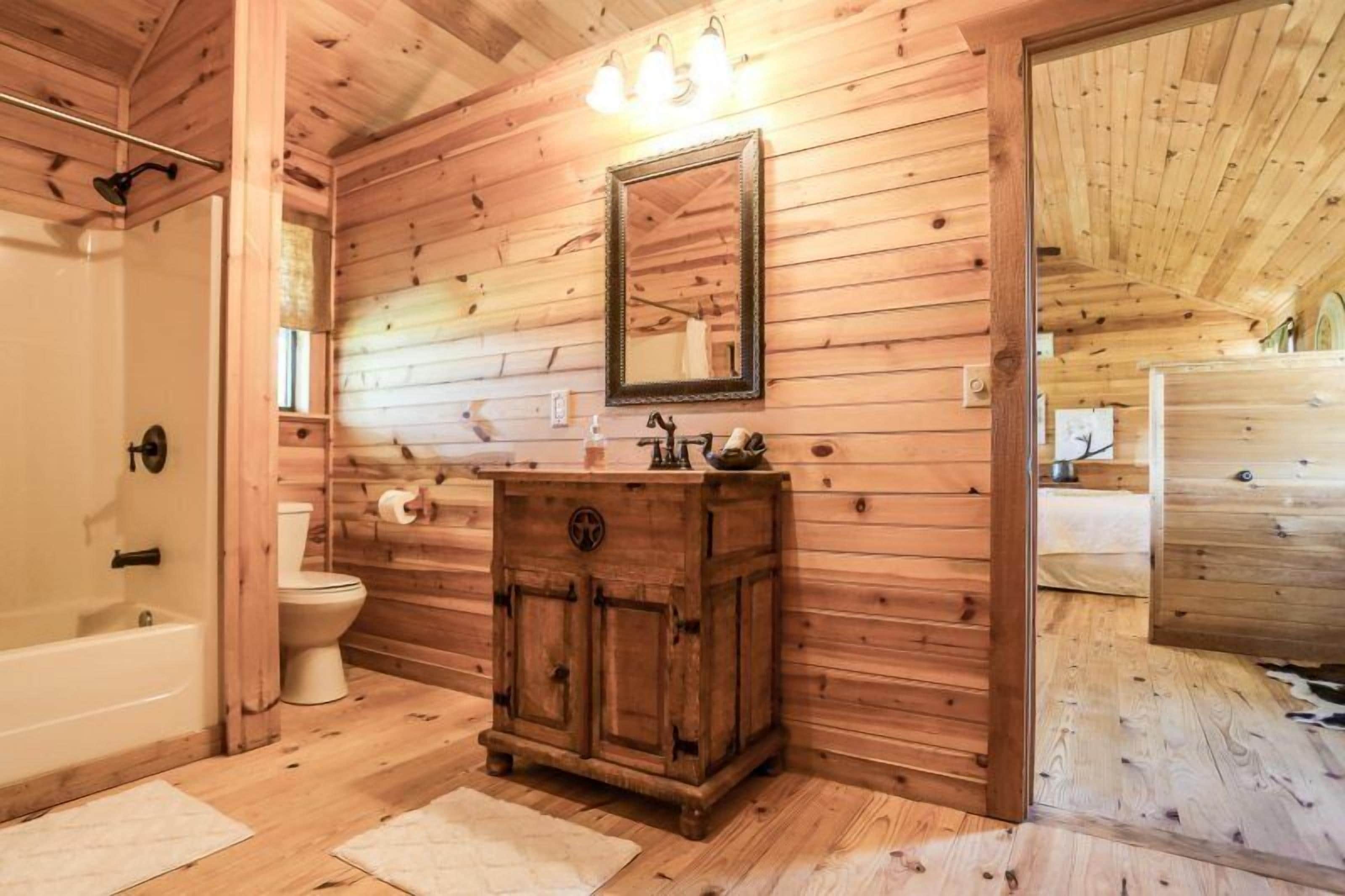 A wooden-paneled bathroom with a wooden cabinet, a mirror, and a bathtub.