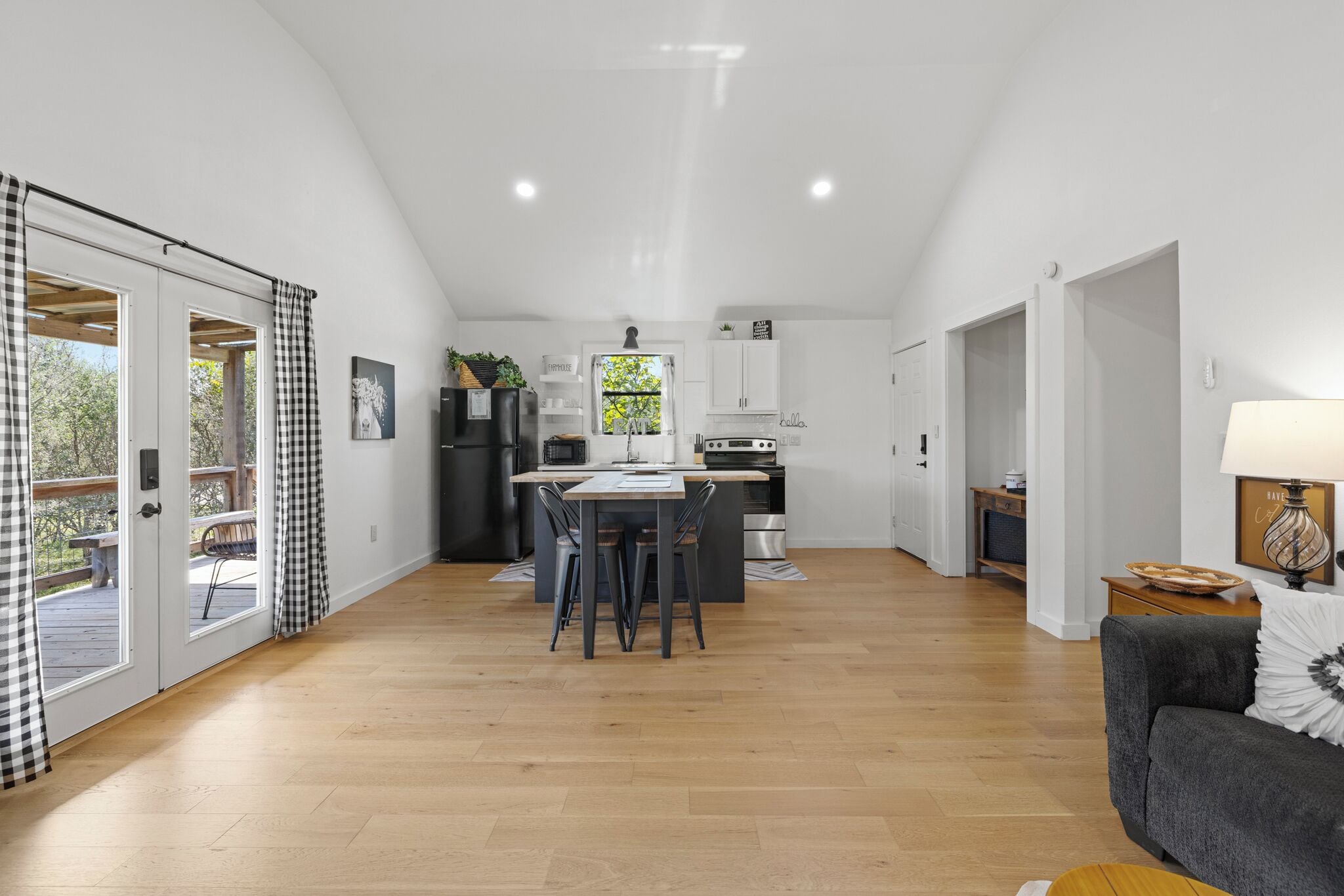 Amplia sala de estar con una mesa de comedor y sillas, una cocina con electrodomésticos modernos y una zona de estar acogedora con un sofá y una lámpara.