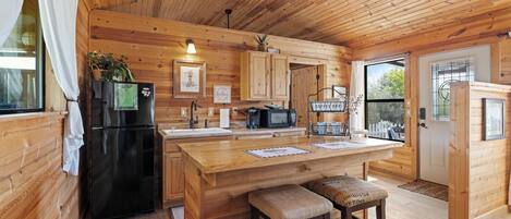 Cocina de cabaña de madera con refrigerador, microondas y barra para café.