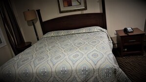 Una habitación de hotel con una cama, una mesita de noche y una lámpara.