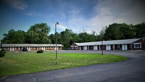 Un motel con varias habitaciones, un estacionamiento y una zona verde.