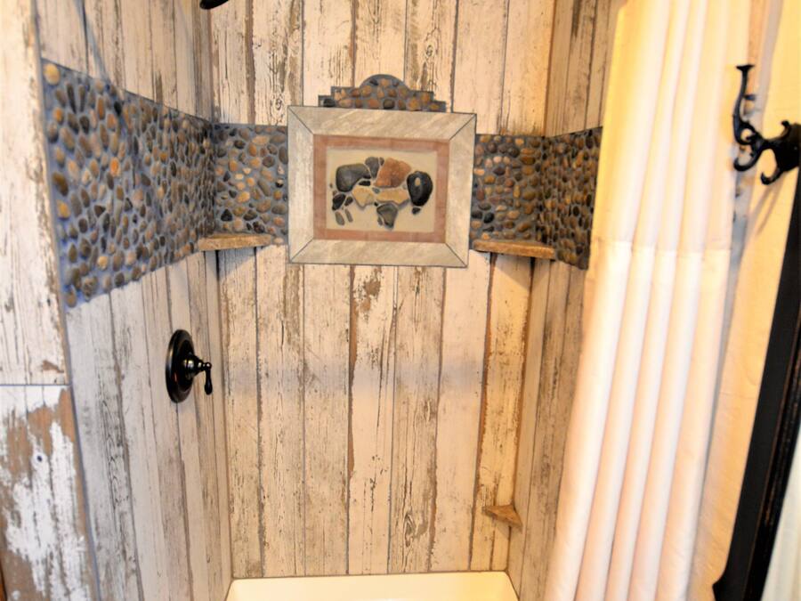 Dutxa amb un fons de fusta, un quadre amb marc i un penjador de tovalloles.