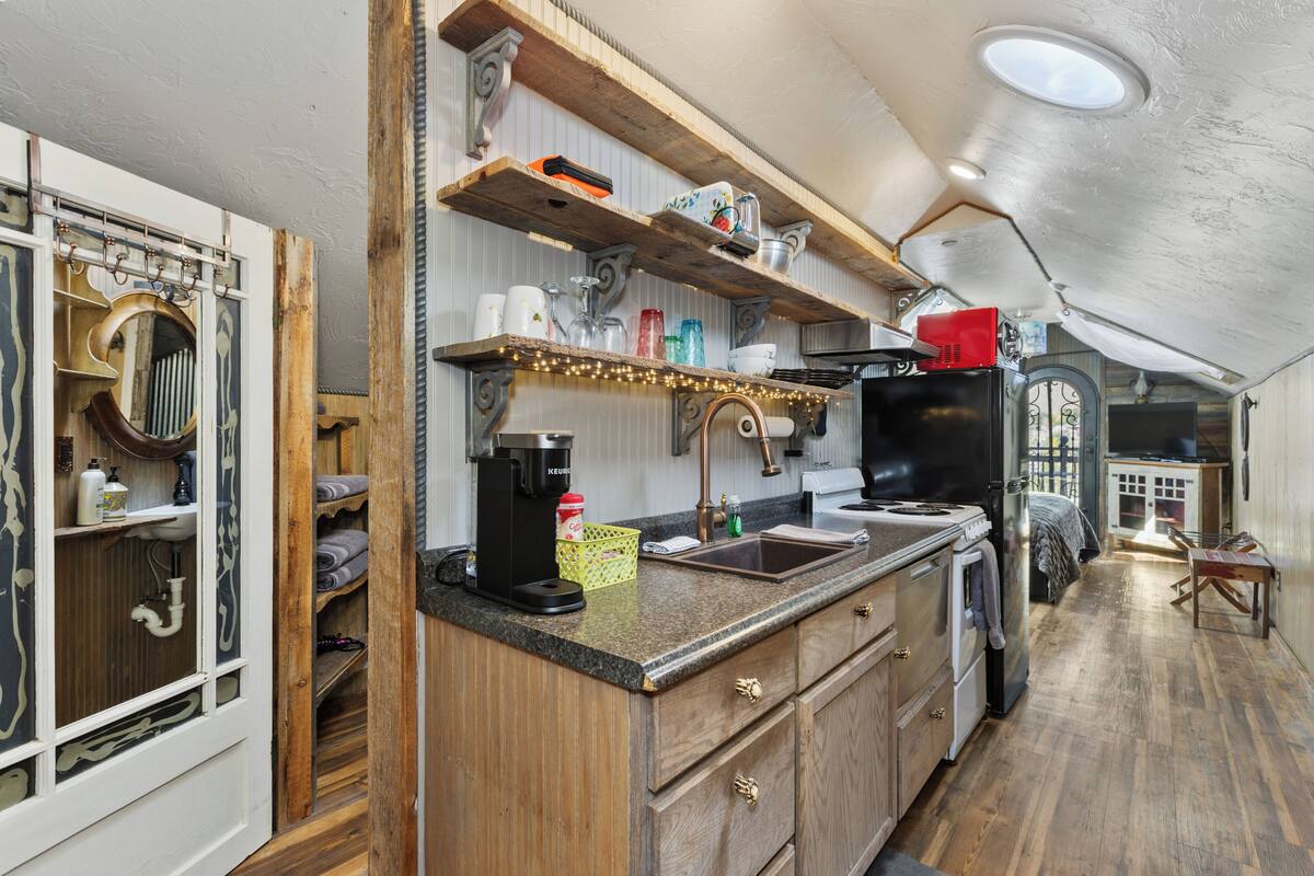 A kitchen with wooden cabinets, a sink, a coffee maker, and a window with curtains.