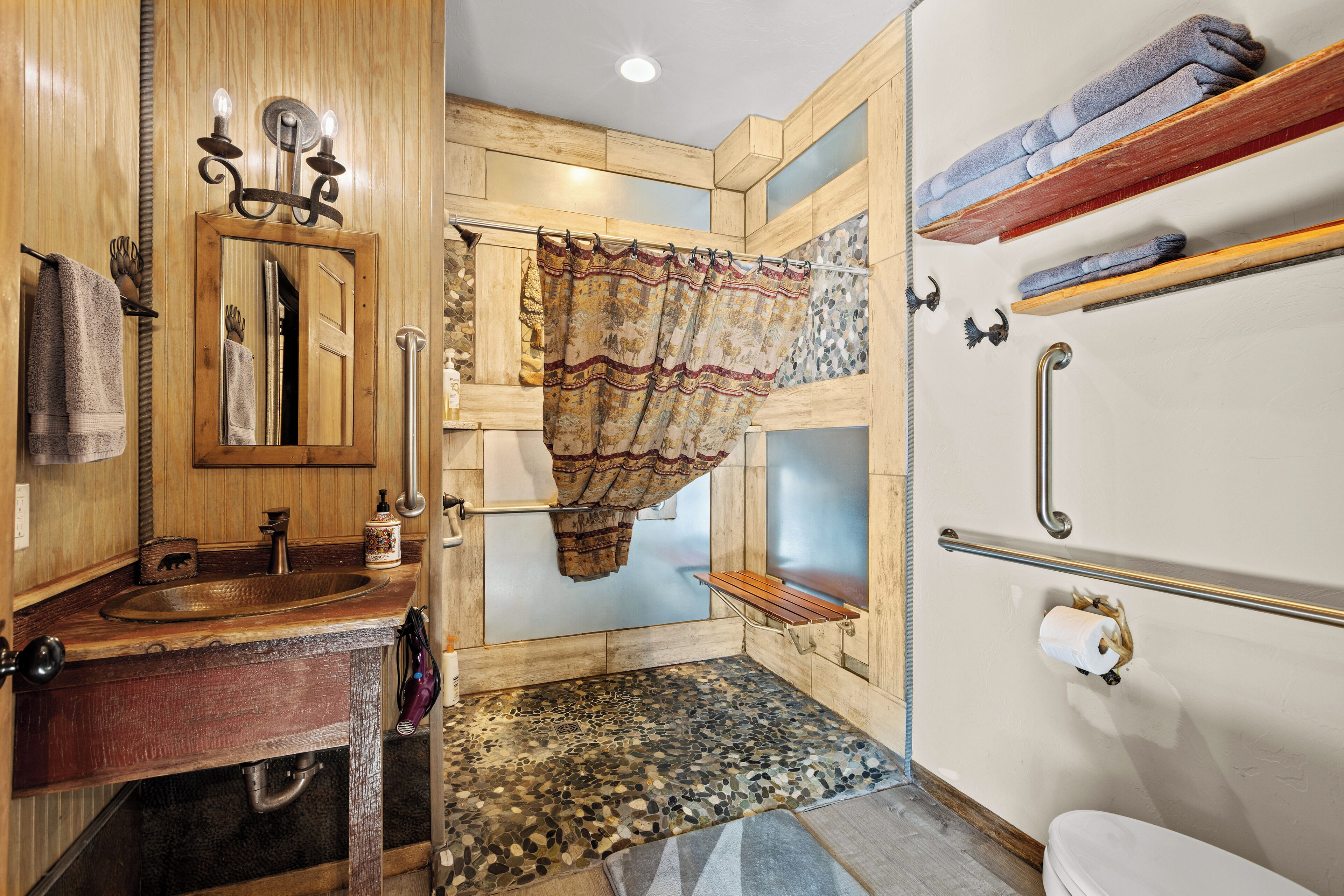 A bathroom with a wooden vanity, a mirror, a sink, a shower area with a curtain, and a toilet.
