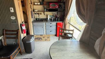 Une cuisine compacte équipée d’un four à micro-ondes, d’un évier et de placards. On y trouve une table à manger avec des chaises et un tapis.