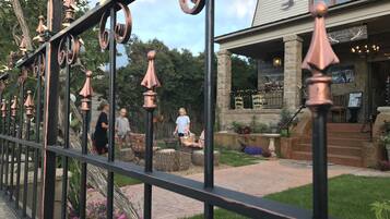 A wrought iron fence with decorative elements, a stone building with a sign, and a pathway leading to a seating area.