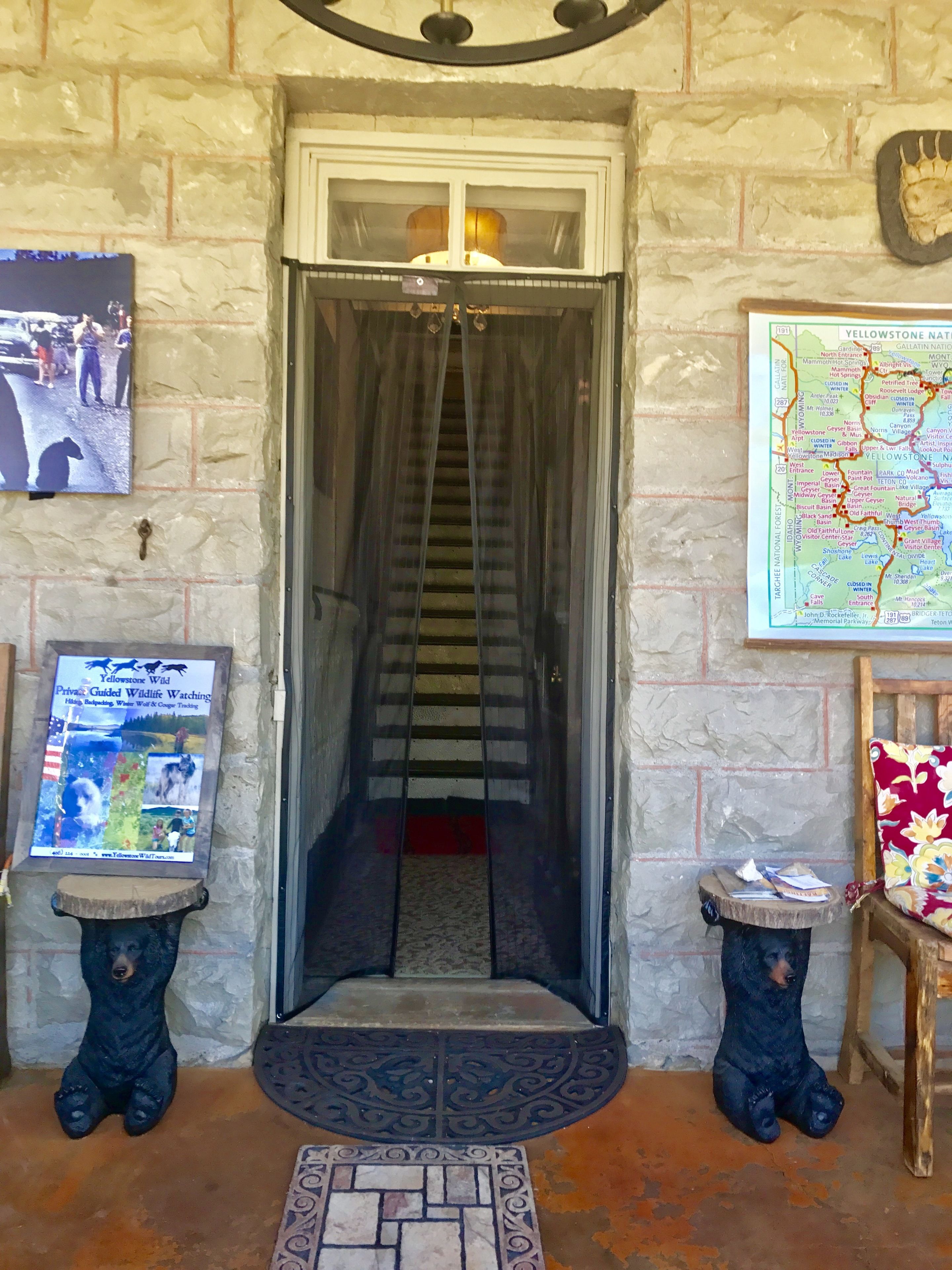 Une entrée aux murs de pierre, avec un escalier menant à une pièce. On peut y voir une carte encadrée et un panneau indiquant un point d’observation de la faune.