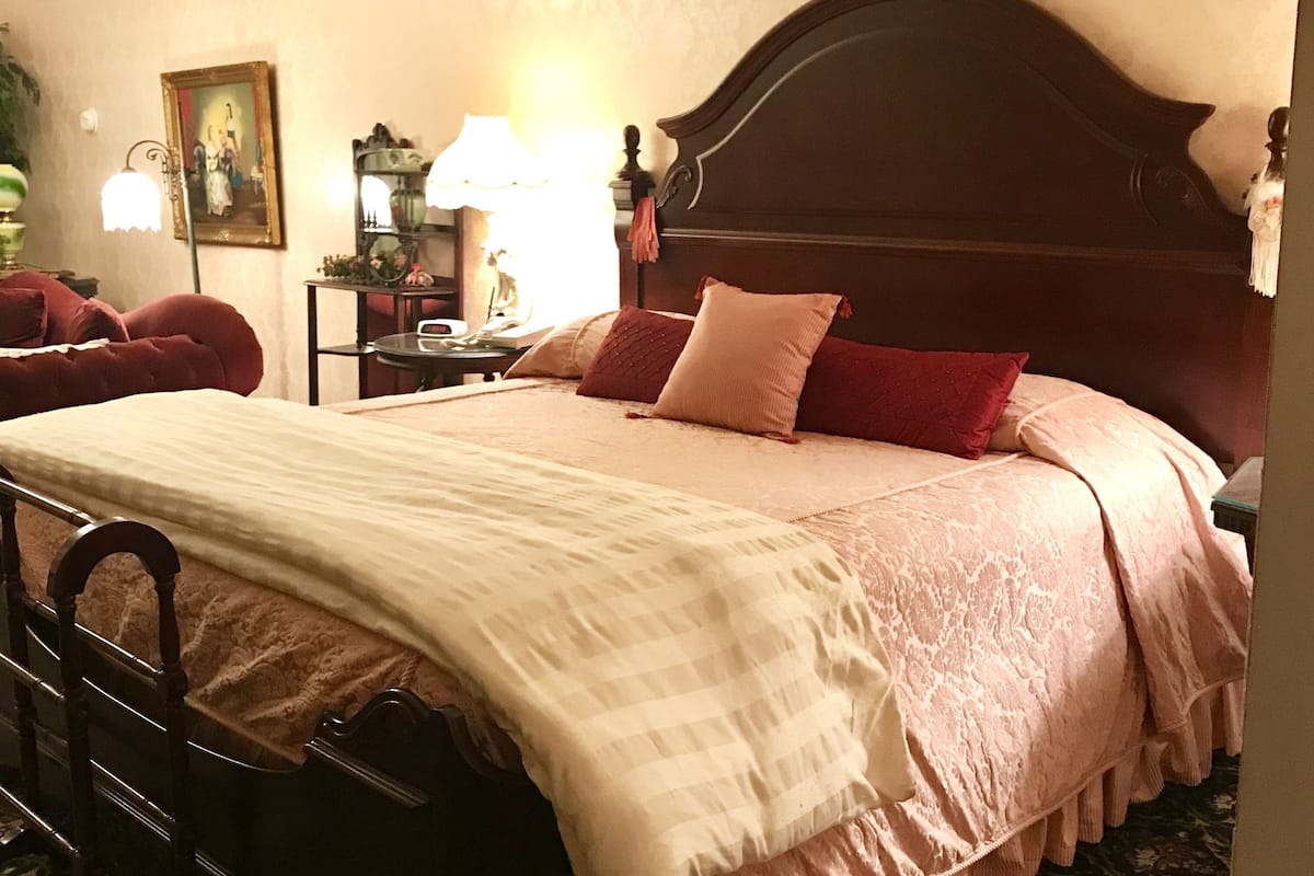 A bedroom with a large bed, a wooden headboard, and a bedside table with a lamp.