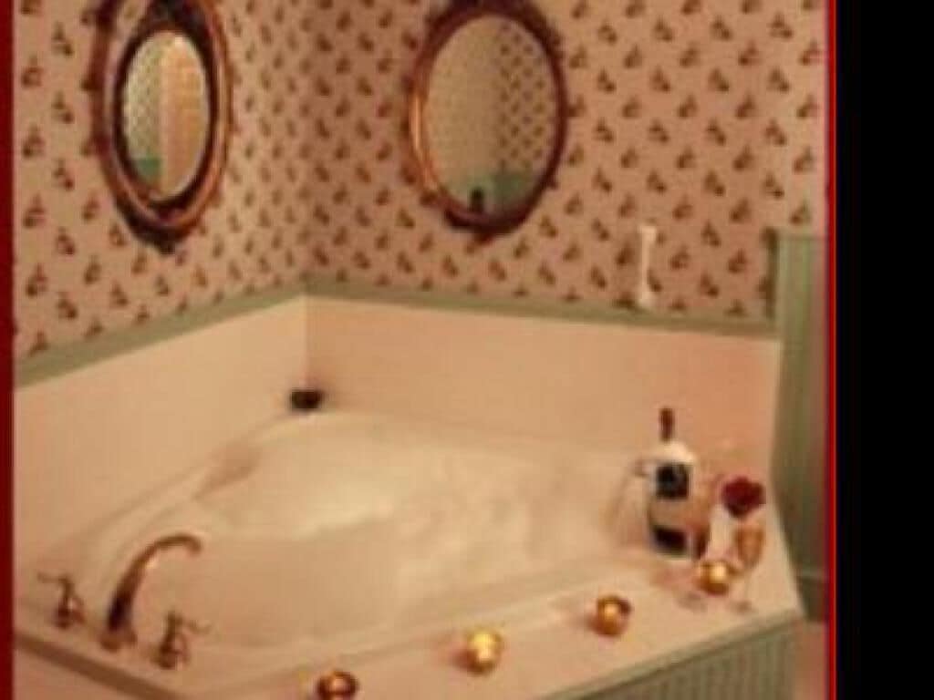 A bathroom with a large bathtub, two round mirrors, and a toilet.