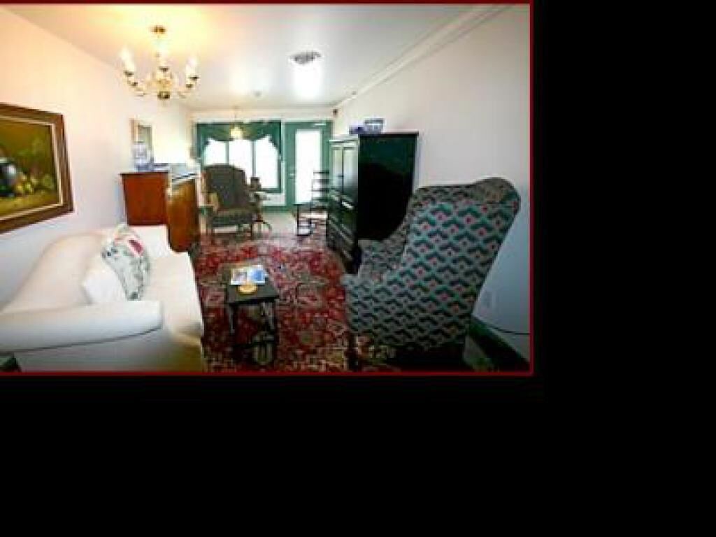 A living room with a white sofa, patterned armchair, and a red carpet.