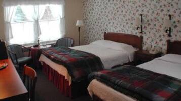 A hotel room with two beds, a desk, a chair, and a window with curtains.