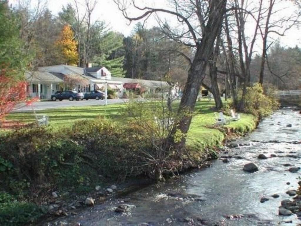 Vista al río con una casa y coches aparcados.