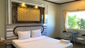 Une chambre d’hôtel dotée d’un grand lit, d’un mur décoratif en marbre, d’une petite table avec des chaises et d’une fenêtre donnant sur un paysage verdoyant.