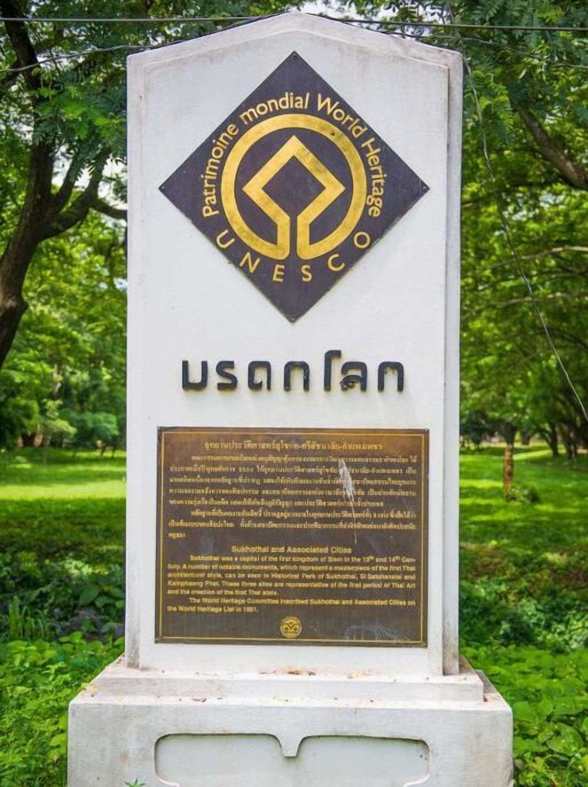A UNESCO World Heritage sign with a plaque in a park.