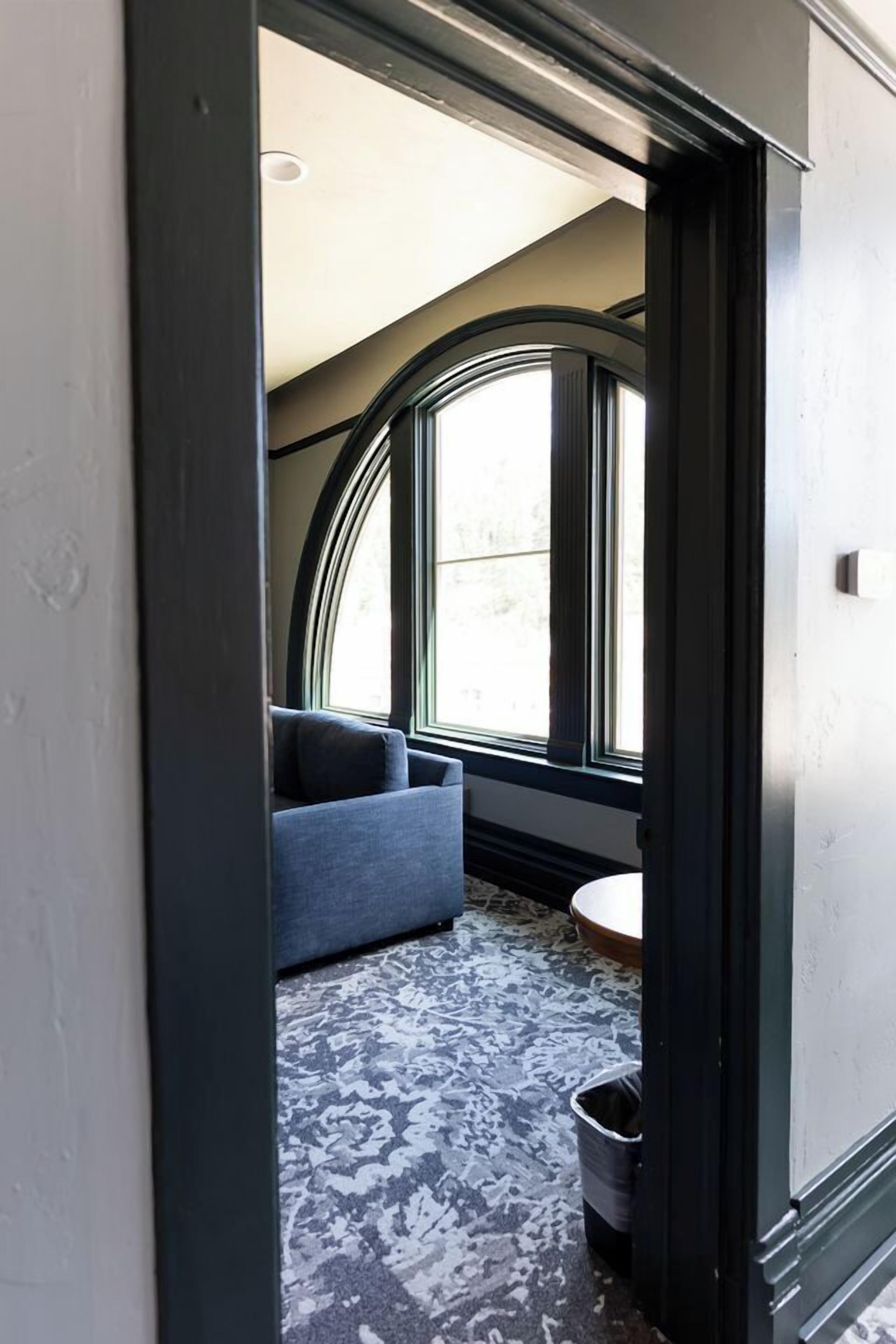 A room with a curved window, a blue sofa, and a patterned carpet.