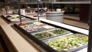 Buffet com diversas opções de comida, incluindo saladas, frutas e legumes.