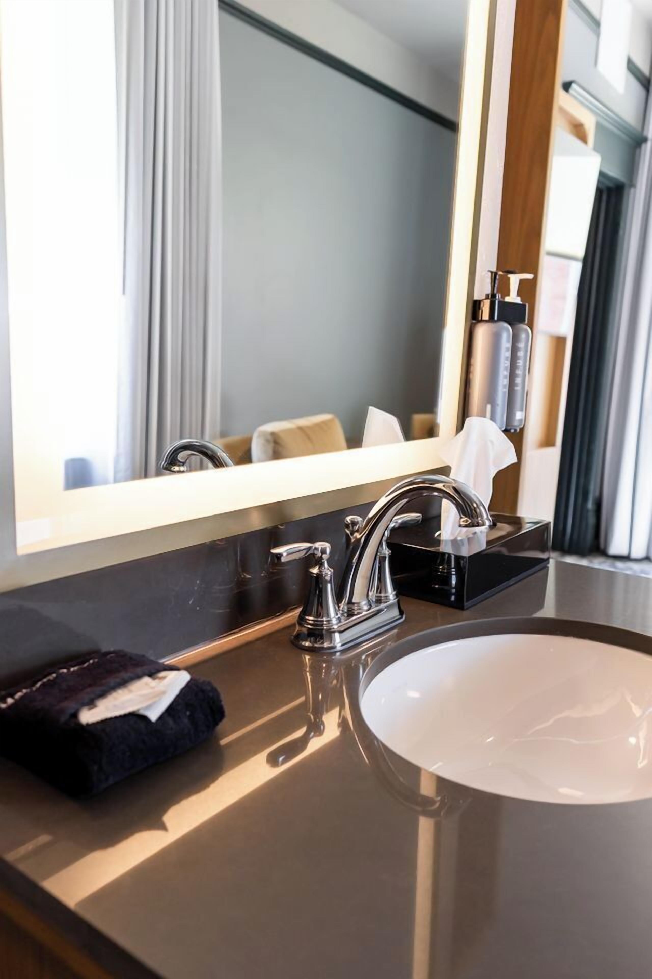 A modern bathroom with a large mirror, a sink, and a towel rack.