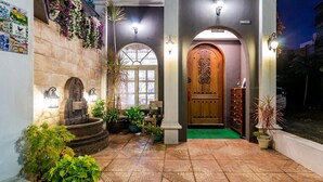 A hotel entrance with a stone facade, a wooden door, and a fountain. - So Funny (Hualien City)