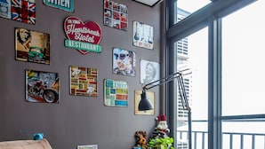A room with a rocking chair, a table with a plant, and various wall decorations including a neon sign and posters. - So Funny (Hualien City)