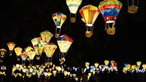 Une scène nocturne où de nombreuses lanternes colorées sont suspendues dans le ciel.